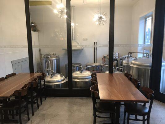 Larger seating for the restaurant and view of some brewing equipment.