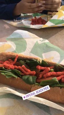 spinach, tomatoes,bell peppers and hot Cheetos in an Italian BMT Sandwich