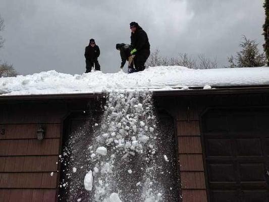 The Roofing Guys hard at work removing snow off a house to help prevent ice dams. Photo courtesy of Syracuse.com