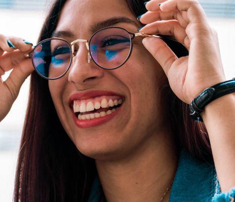 A woman holds a new pair of eyeglasses to her face. At VC Vision, your choice of frames, from affordable to top-end luxury options.