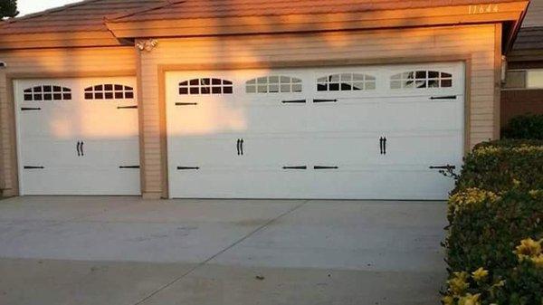 Double and single car garage doors with carriage stamp panels and decorative hardware.Top sections have a cascade ranch inserts.