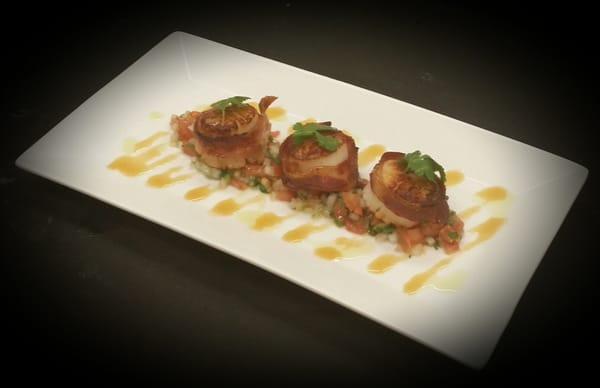 Bacon Wrapped Scallops scallops wrapped in Bourbon bacon served  on a bed of fresh pico de gallo drizzled with a honey sauce.