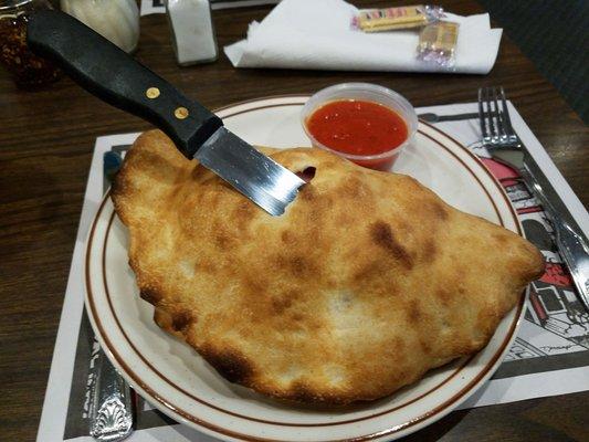 Huge calzone stuffed with sausage and ham, they had to stab it to stay on plate!