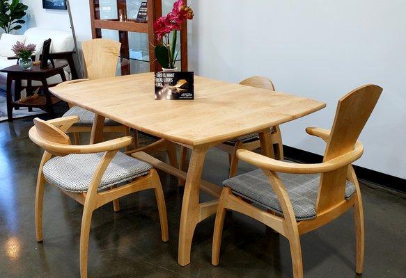 Modern Linnaea maple dining table with low back and tall back chairs.