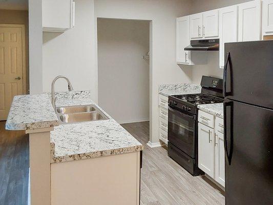 Beautiful renovated kitchen featuring sleek granite countertops, energy efficient appliances, and white shaker cabinetry.