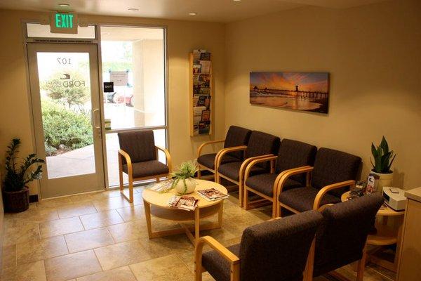 The patient waiting is decorated with comfortable chairs, various reading material and art depicting Huntington Beach landmarks.