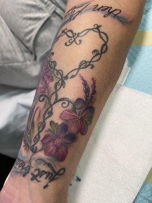 Added flowers around Jeremy  maxfield  work . I do not tattoo words or heavy outlines in my works .