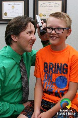 A Doctor of Audiology performing otoscopy on a young patient.