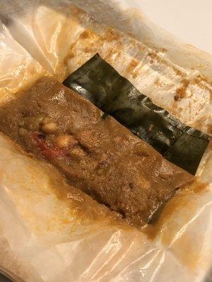 Pasteles wrapped in banana leaf with pork filling.