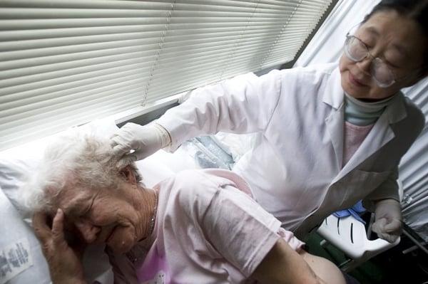 CRAIG DILGER/Daily Herald Margerie White tries to hold still as acupuncturist Dr. Ming-De Yu places a series of needles into the skin on the