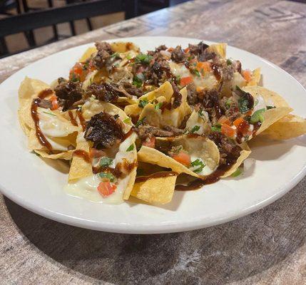 Our Famous Nachos. House fried tortilla chips  smothered with queso brisket, chicken or pulled pork. Topped with Pico de Gallo. Best Seller