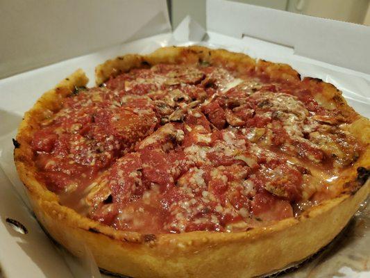 Small deep dish pizza with sausage, mushrooms, and spinach mix