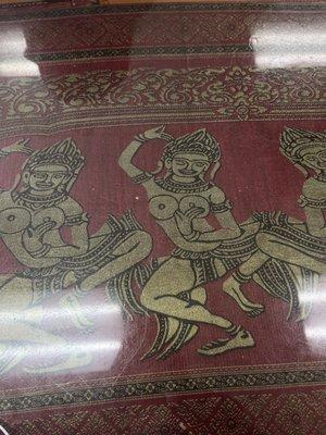 Artwork of apsara dancers on table.