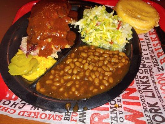 BBQ pork plate sliced with a side of cole slaw and baked beans.