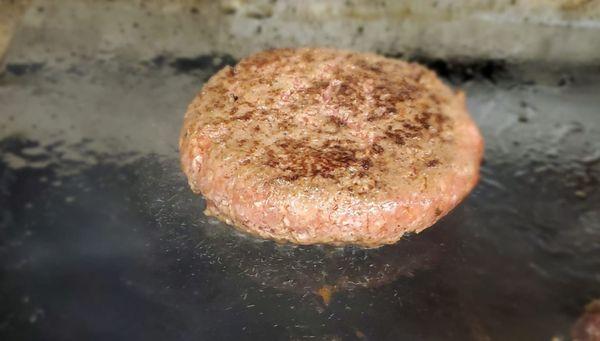 Hand-pattied hamburger on the grill