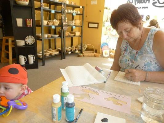 My grandmother painting. In the background are some of the pieces you may paint and examples of completed work.