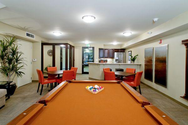 Resident lounge with pool table and kitchen with stainless steel appliances.