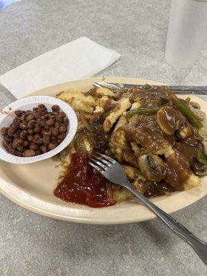 The hamburger steak stacked on toast, fries on top of steak covered with brown gravy. With a side of black eyed peas.