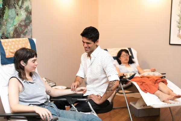 Christian feeling a patients pulse and discussing health history during a Community Acupuncture session