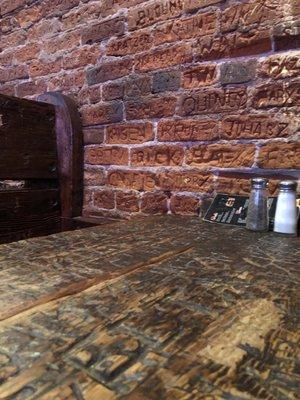 The tables and brick wall are hand carved with the names of employees and patrons.