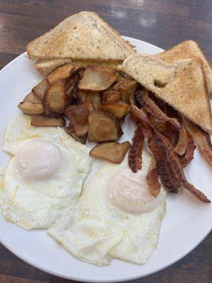 Over-easy eggs, fried potatoes, bacon, and toast.