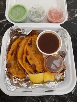 Birria Tacos with lemons, salsa, onions and cilantro, etc