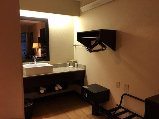 Bathroom vanity, luggage rack, safe, and shelf.