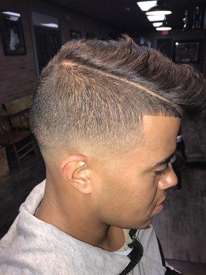 Low skin-tight fade with line up and hard part.   Texturized scissor cut on top.