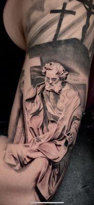 "Captivating saint statue tattoo, showcasing divine artistry and detail. Book now for your spiritual design."