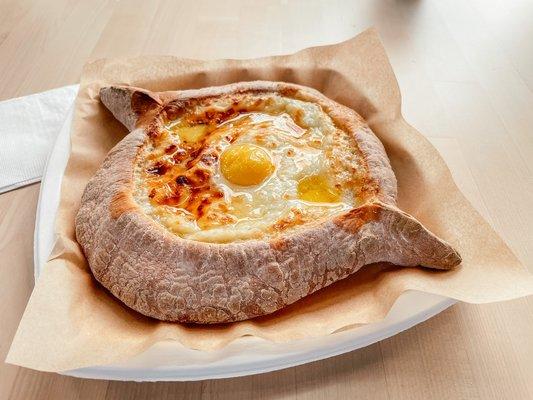 Adjaruli khachapuri (bread boat) - Fluffy bread boat with cheese, grass-fed butter, and egg yolk.