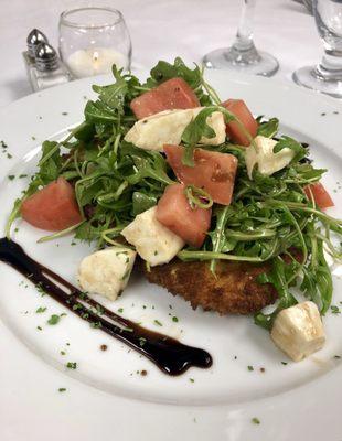 Chicken Milanese topped with a crisp arugula salad, fresh tomato, mozzarella, and balsamic vinaigrette.