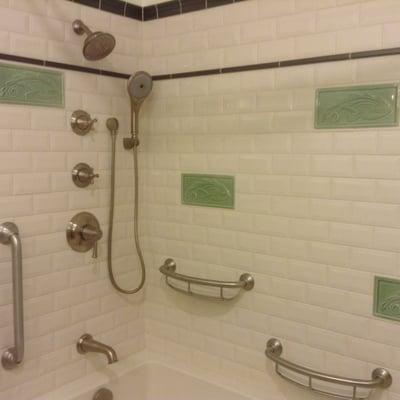 Shower and jacuzzi tub with fixtures and grab bars.