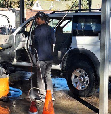 The guy is using a POWER WASHER to clean the inside of my SUV.