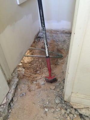 Trench digging through closet and under walls for pipe repair.