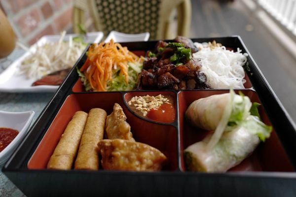 Amazing offering bento box filled with all the best: spring roll, egg roll, vermicelli salad with crispy pork.