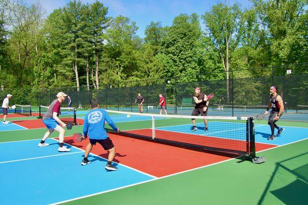 Four men play pickleball at the outdoor pickleball and tennis complex during a doubles pickleball tournament at the Upper Main Line YMCA.