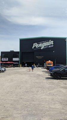 The large parking lot, huge building, and cider joint next door