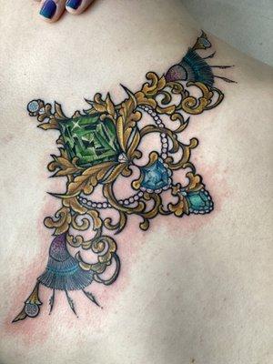 Sternum jewelry tattoo with gems and gold