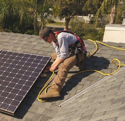 Cameron fixing harness onto solar panel racking structure in preparation for panel cleaning.