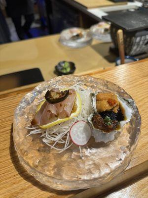 Oyster topped with caviar Uni and a refreshing sauce next to yellowtail jalapeño style sashimi.