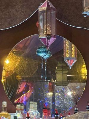 Circular mirror behind bar with reflection of enchanting lights.