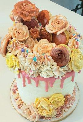 Buttercream roses and hand painted macarons piled high on a yellow striped buttercream cake with pink chocolate drips and sprinkles!