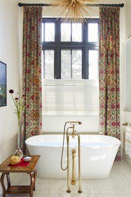 A freestanding tub with custom drapery and curated pieces make this  primary bath a statement.