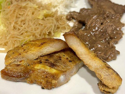 Liempo (grilled pork belly). Background is pancit (vermeclli rice noodles) and bistek (beef steak). The liempo is quite dry.