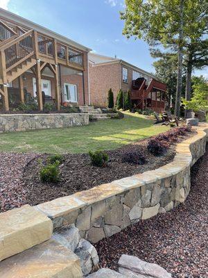 Lakeside retaining wall with rock stairs, lawn, and upper retaining wall.