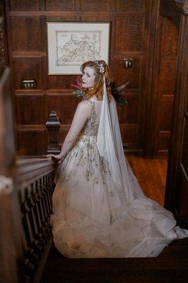 Fall bride walking down staircase with wedding bouquet in vintage victorian estate, mountains, anomalie wedding dress