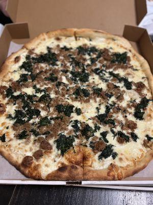 White pizza with added spinach and sausage.