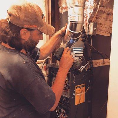 Lead Installer Steven screwing in the flue pipe on a new furnace he installed in Woodstock. Great work Steven!