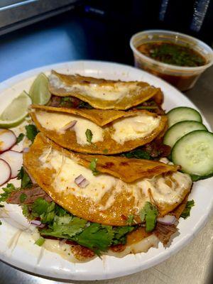 Quesabirria Tacos- 3 Panfried tortillas filled w/shredded birria beef malted mozzarella. onions, cilantro, limes, and a side of consomé!.