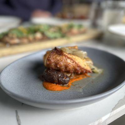 Charred octopus with potatoes. Background: mushroom flatbread